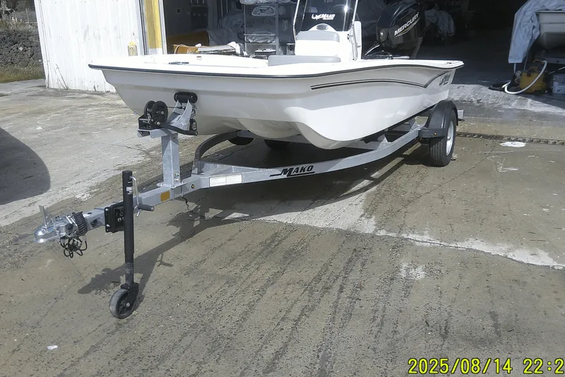 Slide: The Image of 2024 Mako Pro Skiff 15 CC boat on trailer, parked outside a garage. - 4