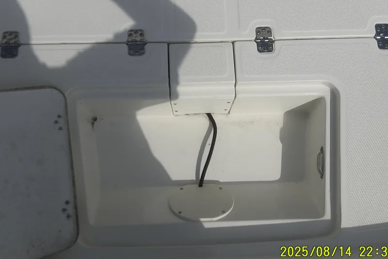 Slide: The Image of 2024 Mako Pro Skiff 15 CC storage compartment with open hatch and visible wiring. - 9