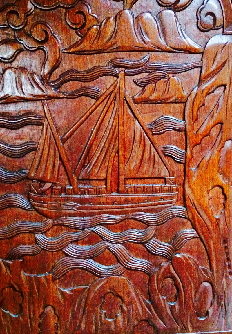 Slide: The Image of Intricate wooden carving of a sailboat, Formosa 41, 1971, with waves and mountains. - 25