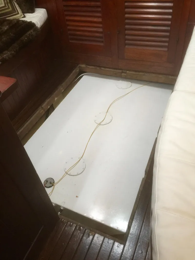 Slide: The Image of Interior view of a 1971 Formosa 41 sailboat, featuring a wooden floor and storage compartment. - 29