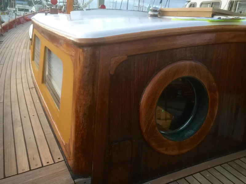 Slide: The Image of 1971 Formosa 41 yacht with wooden deck and cabin, featuring a round porthole window. - 54