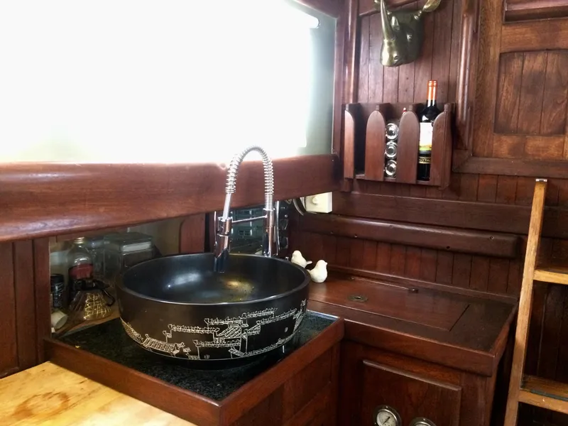 Slide: The Image of Vintage 1971 Formosa 41 yacht kitchen with wooden cabinetry and decorative black sink. - 9