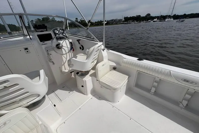 Slide: The Image of 2007 Seahunt VICTORY 225 boat interior with steering wheel and seating, docked on calm water. - 12
