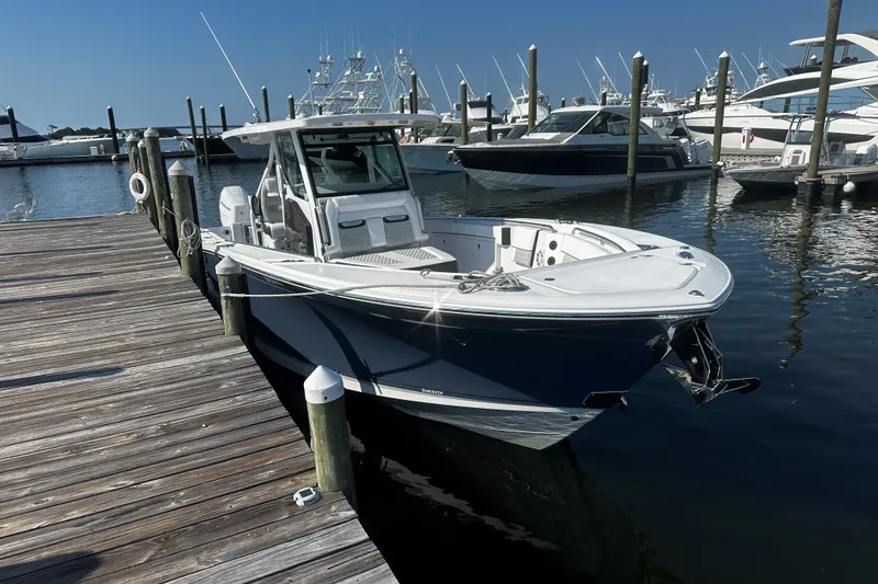 Slide: The Image of 2025 Blackfin 332 CC boat docked at marina, surrounded by other vessels. - 2