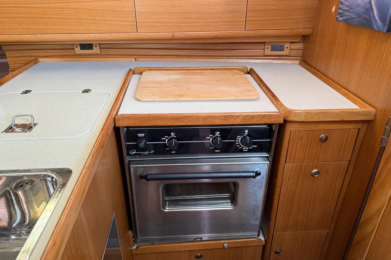 Slide: The Image of Galley kitchen in 2011 Catalina 355 sailboat with stove, sink, and wooden cabinetry. - 31