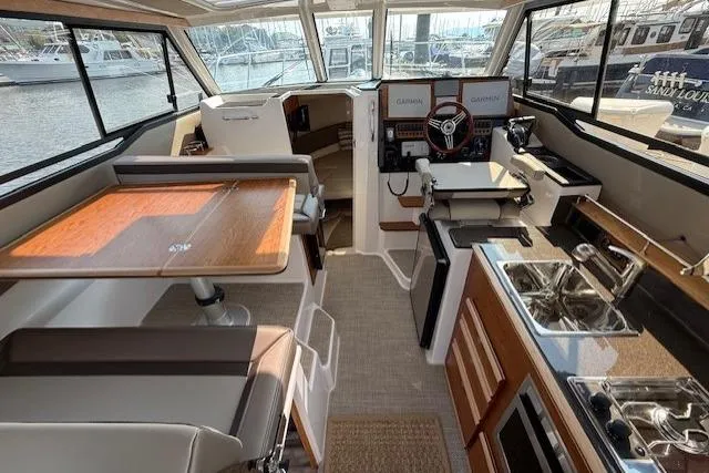 Slide: The Image of 2024 Cutwater C-288 Coupe interior with modern helm, dining area, and kitchenette. - 7