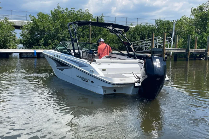 Slide: The Image of 2021 Monterey M225 boat navigating a calm waterway near a dock. - 13