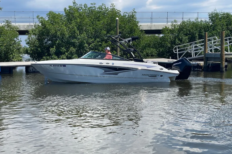 Slide: The Image of 2021 Monterey M225 boat on water near dock, surrounded by greenery. - 14