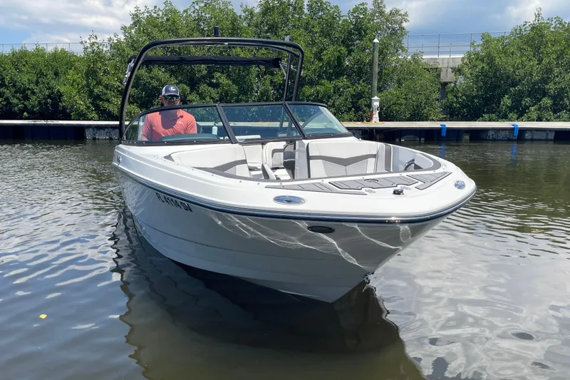 Slide: The Image of 2021 Monterey M225 boat on water, with driver, surrounded by greenery. - 18