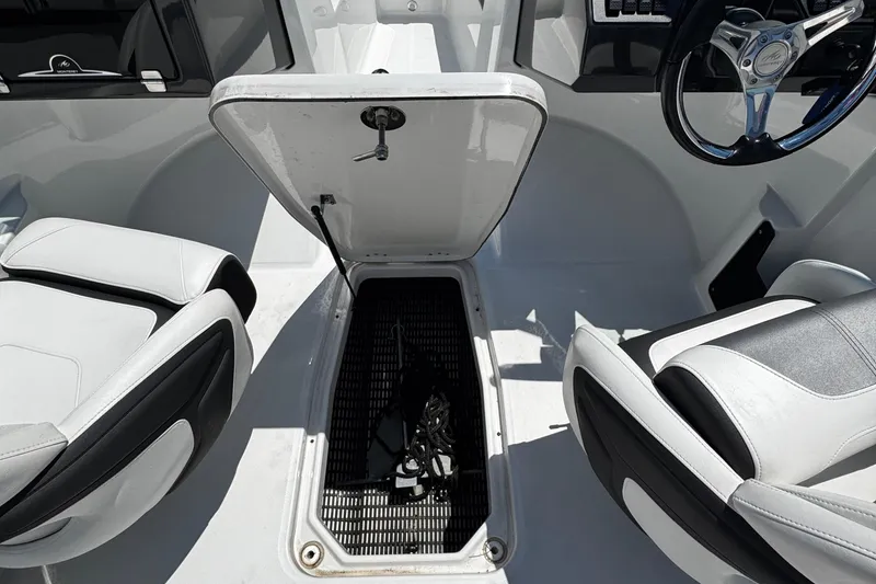 Slide: The Image of 2021 Monterey M225 boat interior with open storage compartment and steering wheel. - 35
