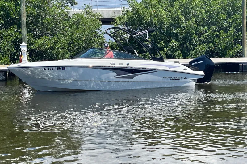 Slide: The Image of 2021 Monterey M225 boat on water near dock, surrounded by lush greenery. - 7
