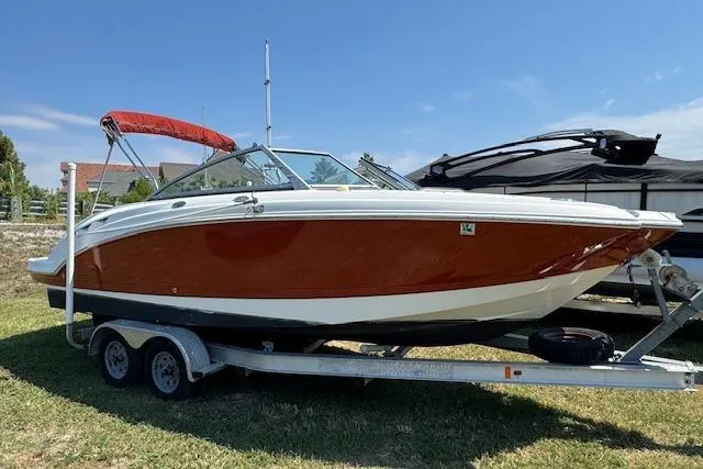 The Image of 2008 Chaparral Sunesta 224 boat on trailer with red hull and canopy. - 1