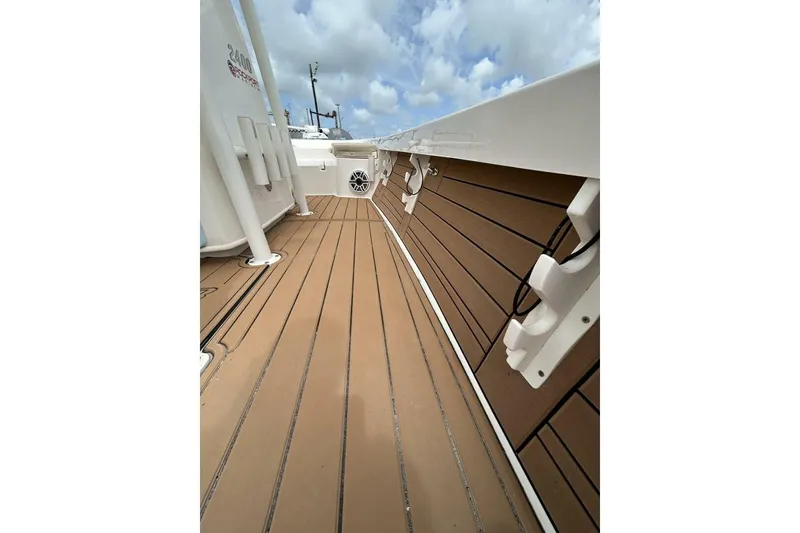 Slide: The Image of 2021 Pathfinder 2400 TRS boat deck with wood finish and rod holders under a cloudy sky. - 11