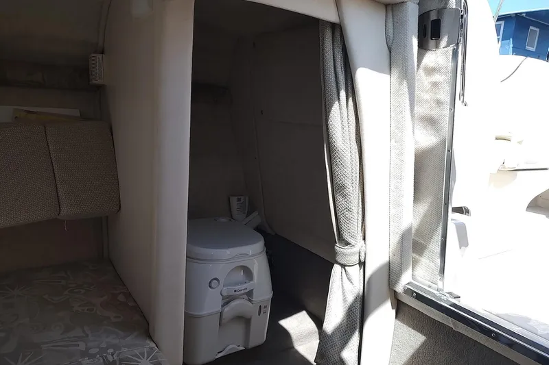 Slide: The Image of 2004 Sea Ray 215 Weekender cabin interior with portable toilet and seating area. - 10