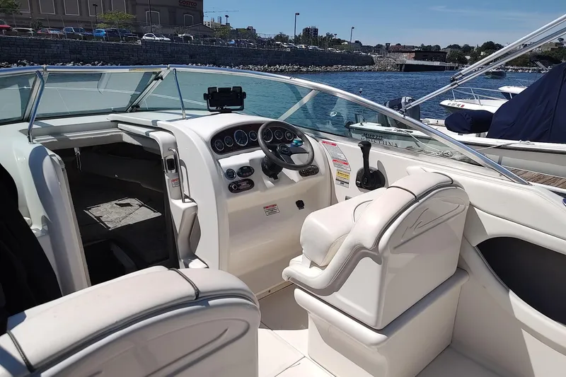 Slide: The Image of 2004 Sea Ray 215 Weekender boat interior with steering wheel and seating, docked by the water. - 11