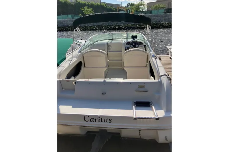 Slide: The Image of 2004 Sea Ray 215 Weekender boat with canopy, docked by the water. - 2