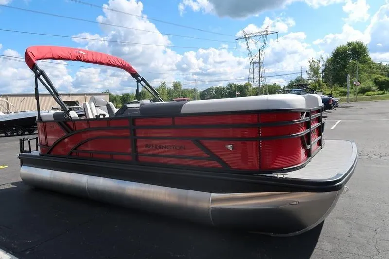 Slide: The Image of 2026 Bennington S Quad Bench 20 SSR pontoon boat with red accents in a parking lot. - 5