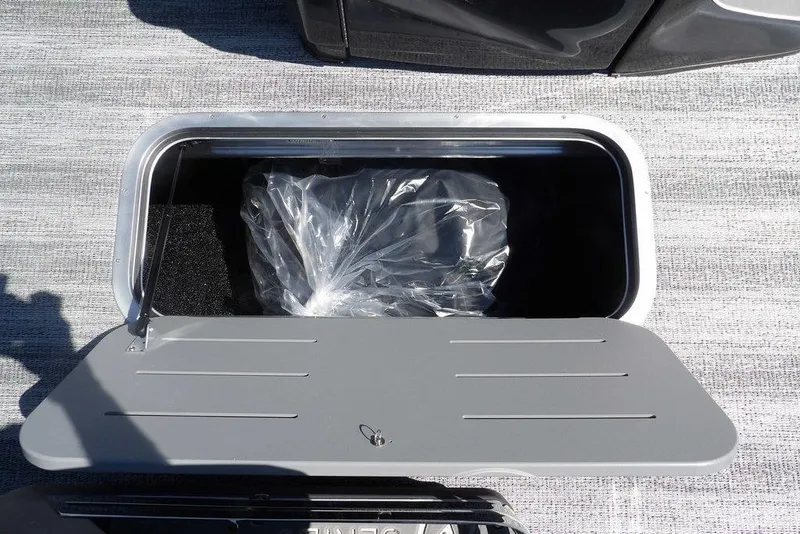 Slide: The Image of Storage compartment on 2026 Bennington M Swingback 24 MSB boat, open with plastic-wrapped item inside. - 23