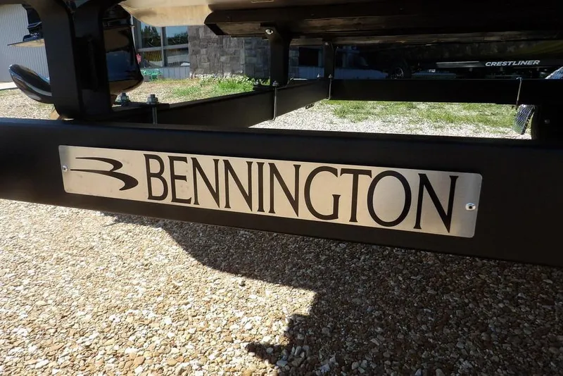 Slide: The Image of 2026 Bennington M Swingback 24 MSB boat trailer with logo on gravel surface. - 54