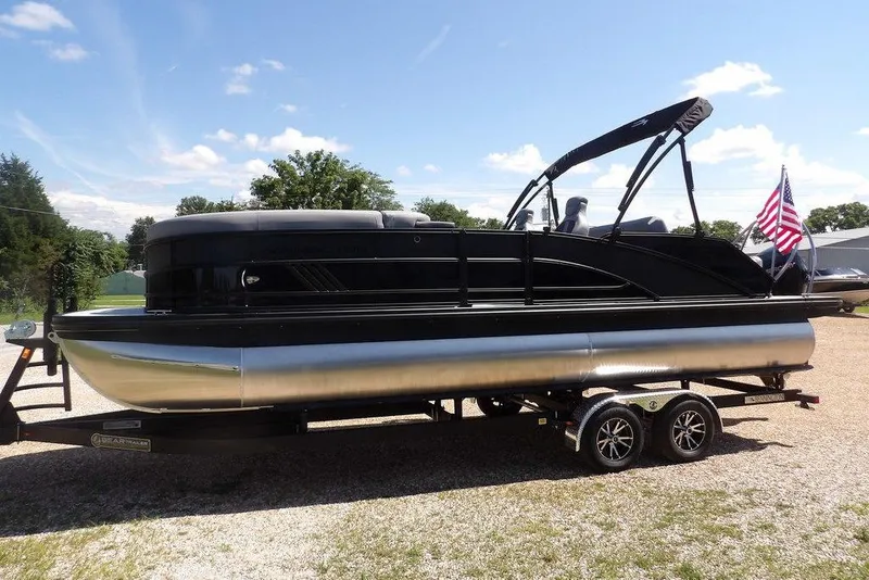 Slide: The Image of 2026 Bennington M Swingback 24 MSB pontoon boat on trailer, sunny day, American flag. - 6