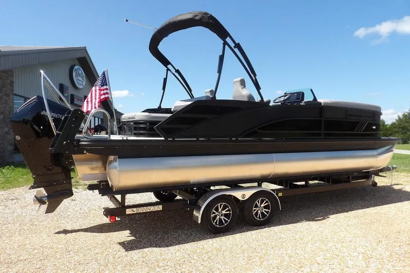 Slide: The Image of 2026 Bennington M Swingback 24 MSB pontoon boat on trailer, American flag, sunny day. - 8