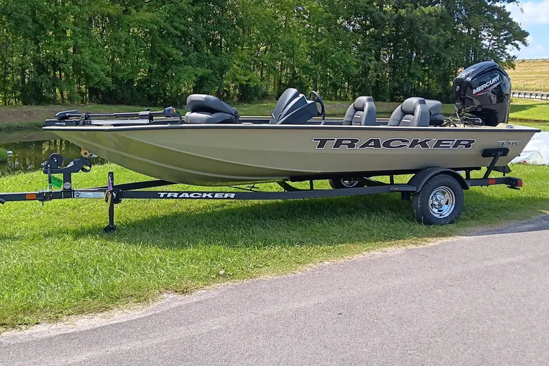 Slide: The Image of 2026 Tracker Pro Team 175 boat on trailer, parked on grass near a pond. - 3
