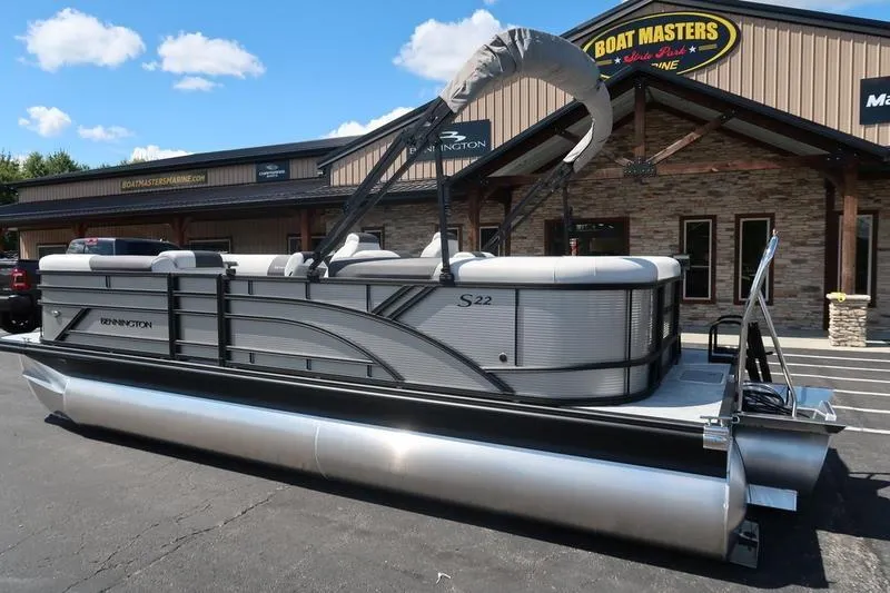 Slide: The Image of 2026 Bennington S Quad Bench 22 SSR pontoon boat parked outside dealership. - 2