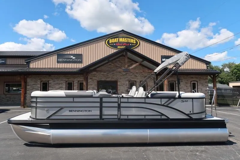 Slide: The Image of 2026 Bennington S Quad Bench 22 SSR pontoon boat at dealership under blue sky. - 6
