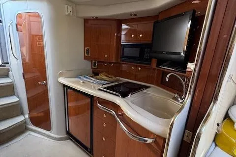 Slide: The Image of 2001 Sea Ray 340 Amberjack interior kitchen with wood cabinets, sink, and appliances. - 21