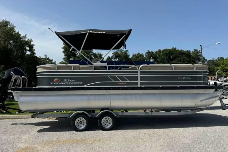 The Image of 2024 Sun Tracker Party Barge 24 DLX pontoon boat on trailer, parked outdoors. - 0