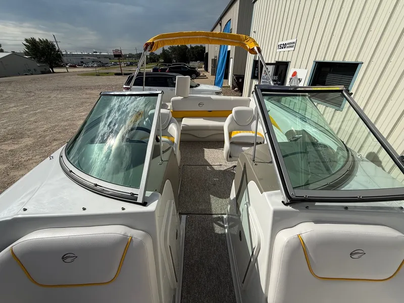 Slide: The Image of 2012 Crownline 225 SS boat with yellow accents, parked outdoors near a building. - 13
