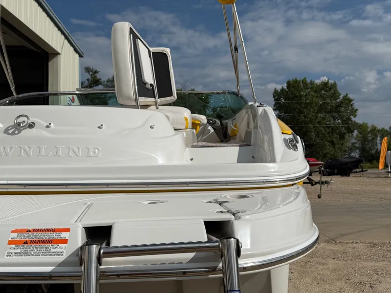 Slide: The Image of 2012 Crownline 225 SS boat, rear view, docked outdoors under a partly cloudy sky. - 23