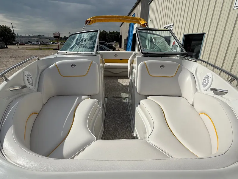Slide: The Image of 2012 Crownline 225 SS boat interior with white and yellow seating, parked outdoors. - 3