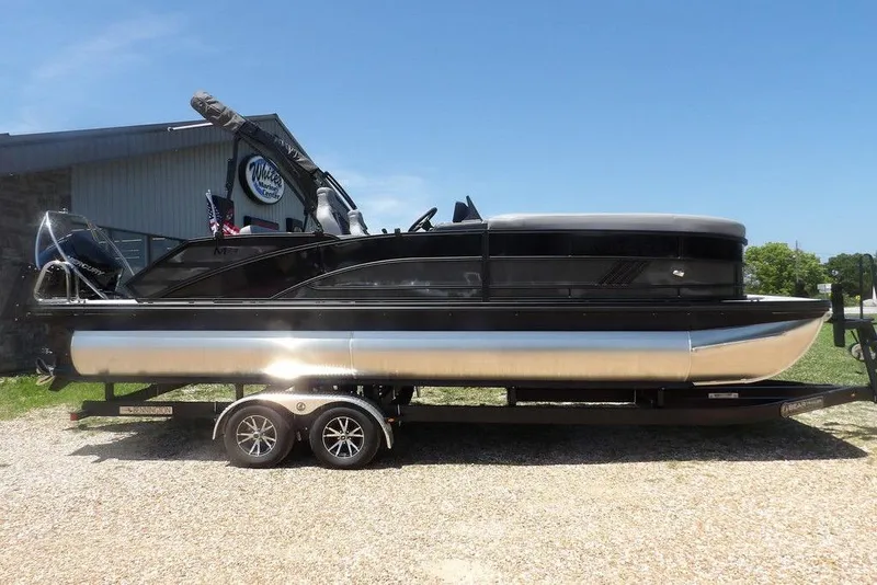 Slide: The Image of 2025 Bennington M Swingback 24 MSB pontoon boat on trailer, sunny day. - 10