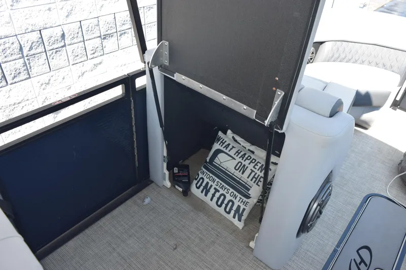 Slide: The Image of 2020 Harris Solstice 230 boat interior with storage compartment and decorative pillow. - 21