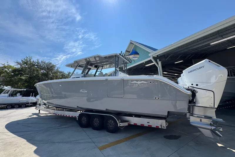 Slide: The Image of 2026 Invincible 40 Catamaran on trailer, parked outdoors under clear blue sky. - 17
