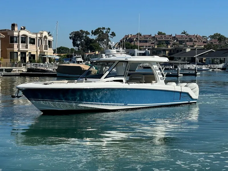 Slide: The Image of 2019 Boston Whaler 350 Realm boat on calm water near luxury waterfront homes. - 0