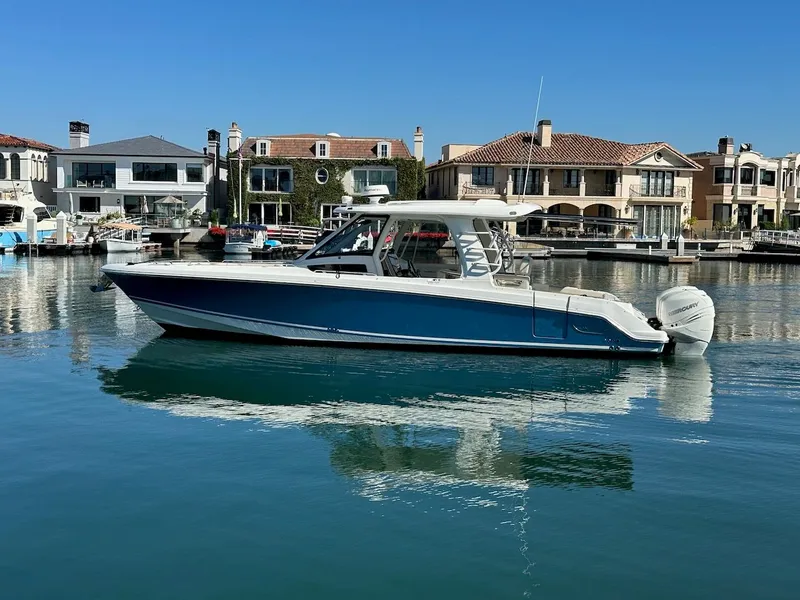 Slide: The Image of 2019 Boston Whaler 350 Realm boat docked in a scenic waterfront area. - 1