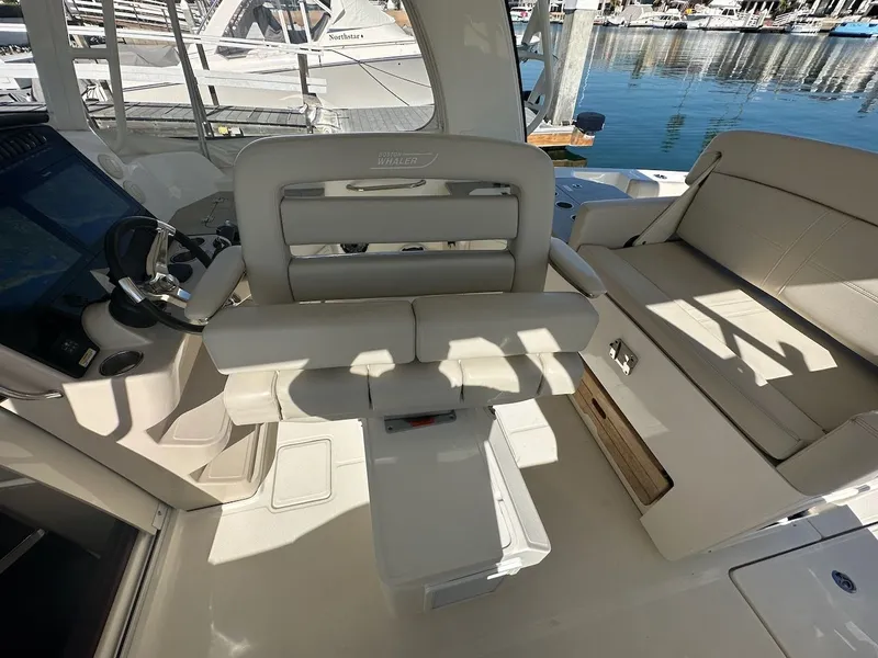 Slide: The Image of 2019 Boston Whaler 350 Realm interior with helm and seating area, docked at marina. - 18