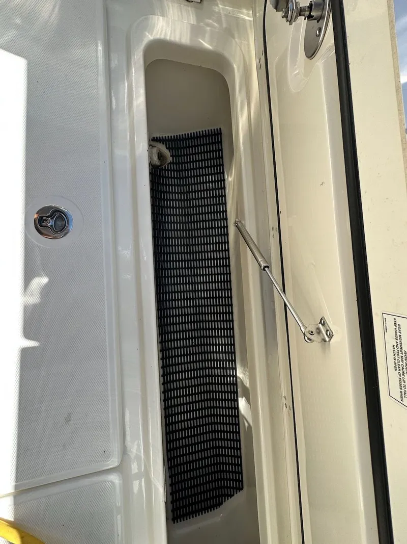 Slide: The Image of 2019 Boston Whaler 350 Realm storage compartment with black mat and hydraulic support. - 42