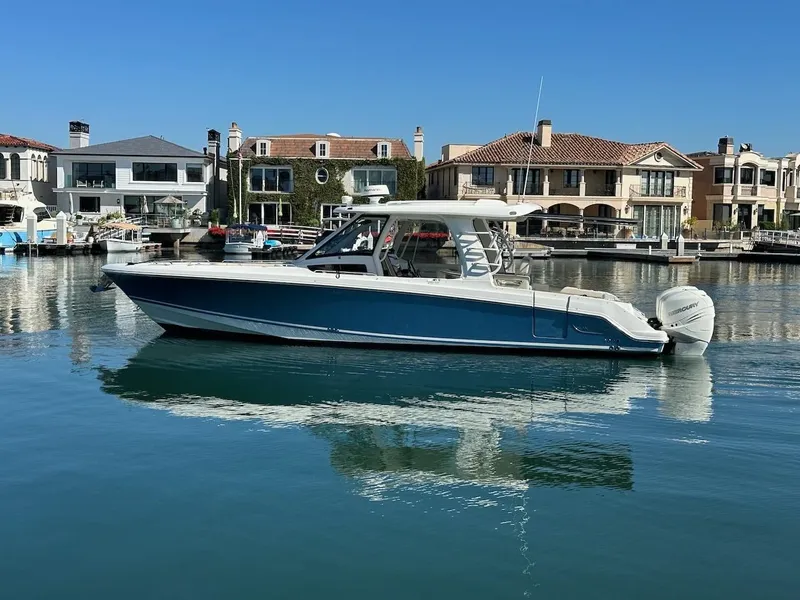 Slide: The Image of 2019 Boston Whaler 350 Realm boat docked in a serene waterfront setting. - 49