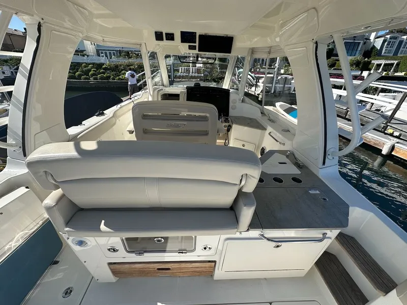 Slide: The Image of 2019 Boston Whaler 350 Realm interior with seating and helm, docked at marina. - 6