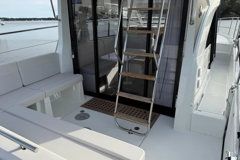 Slide: The Image of 2026 Beneteau Antares 11 Fly yacht interior with seating and ladder, docked by the water. - 12
