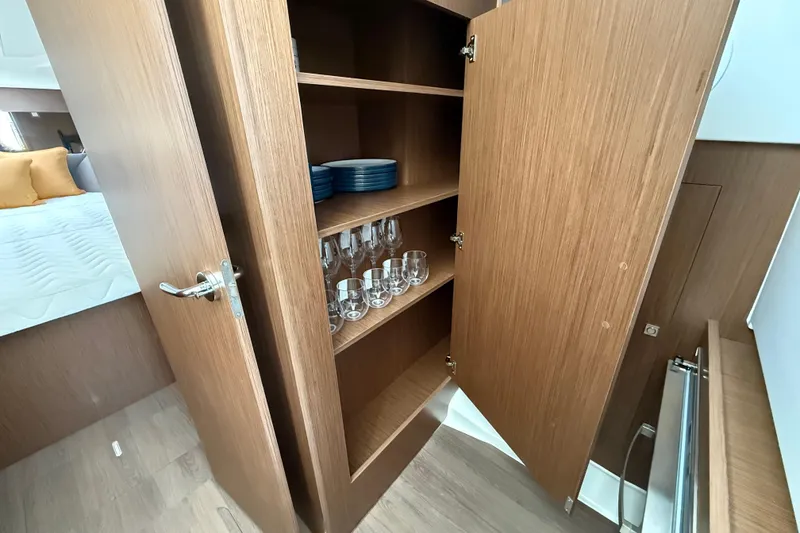 Slide: The Image of 2026 Beneteau Antares 11 Fly interior cabinet with glassware and plates. - 19
