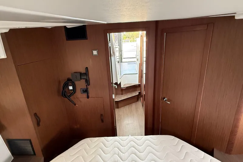 Slide: The Image of 2026 Beneteau Antares 11 Fly cabin interior with wood finish and cozy bed. - 24
