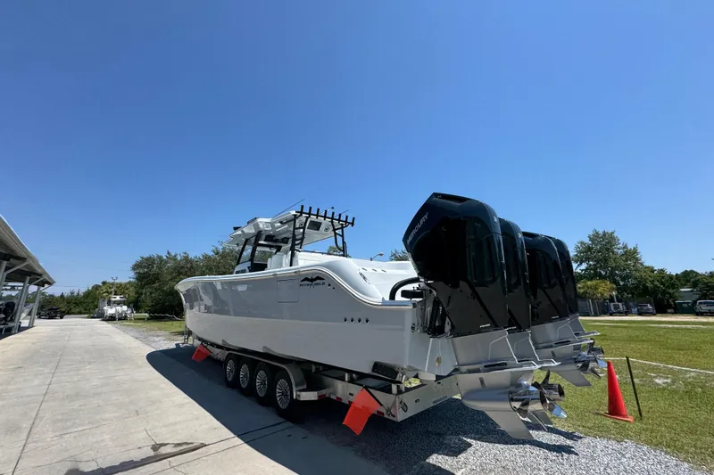 Slide: The Image of 2026 Invincible 46 Catamaran with triple outboard engines on a trailer, under clear blue sky. - 13