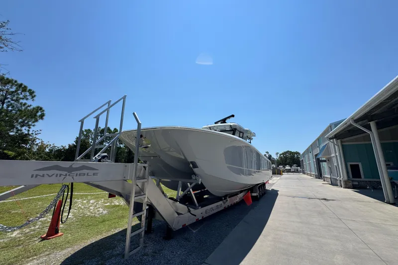 Slide: The Image of 2026 Invincible 46 Catamaran on trailer under clear blue sky. - 14