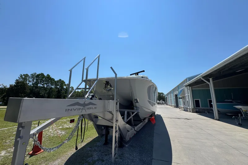 Slide: The Image of 2026 Invincible 46 Catamaran on trailer, parked outdoors under clear blue sky. - 15