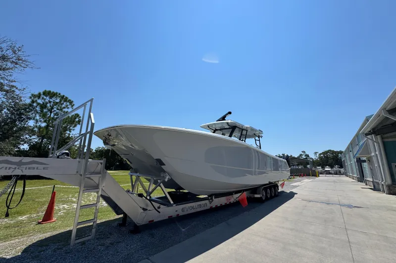 Slide: The Image of 2026 Invincible 46 Catamaran on trailer under clear blue sky. - 2