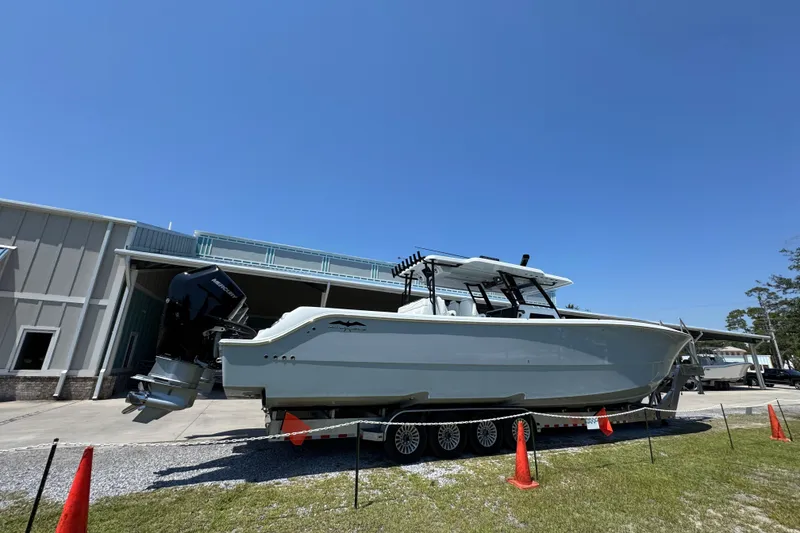Slide: The Image of 2026 Invincible 46 Catamaran on trailer, parked outside a building under clear blue sky. - 8